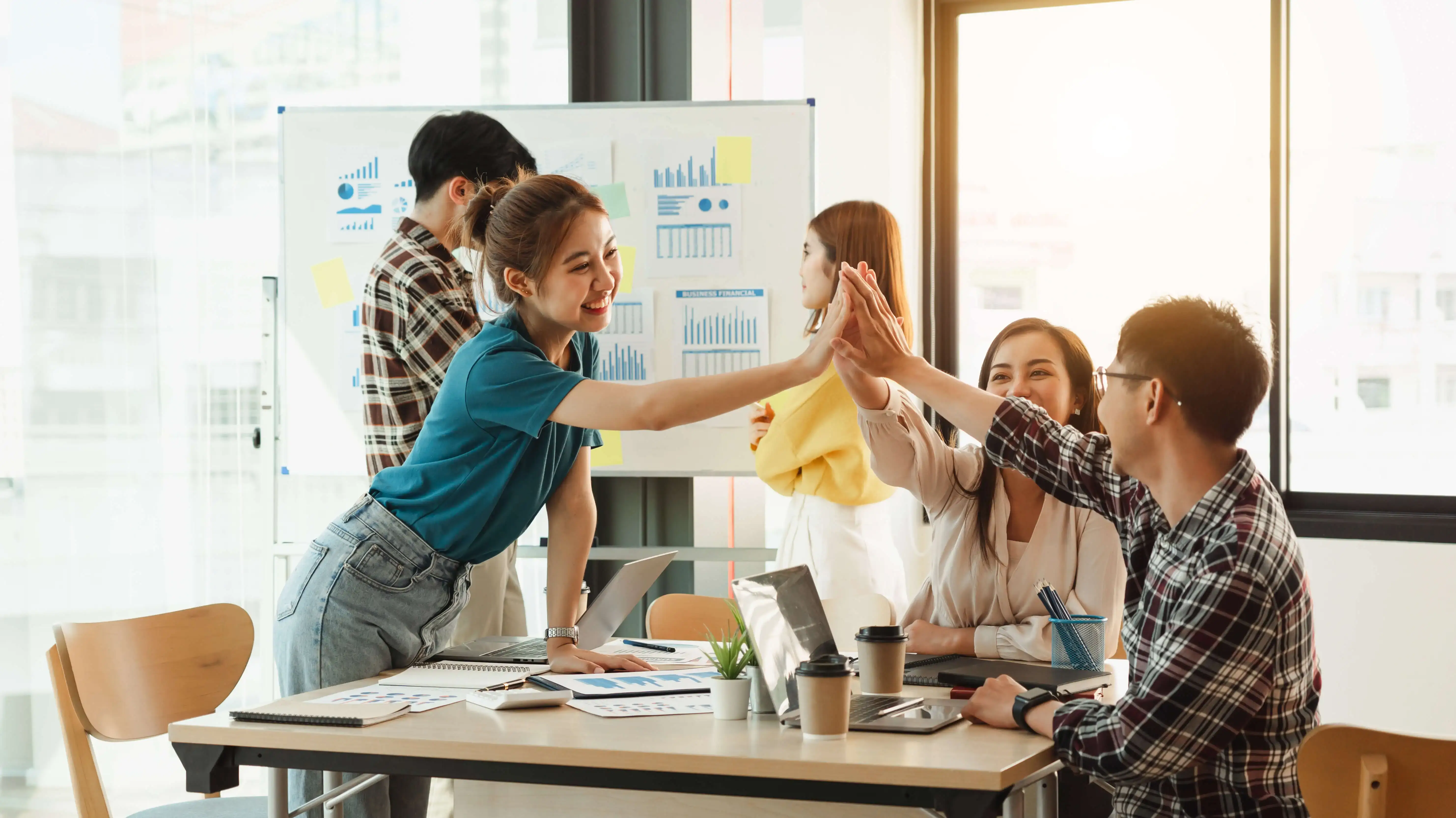 Businesswoman showing colleagues note on whiteboard during meeting